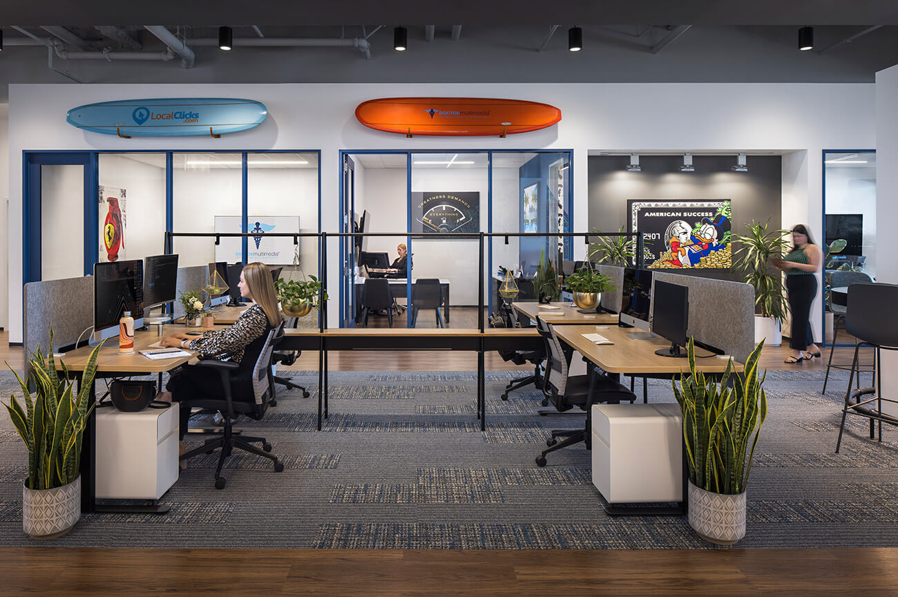 Inside the Doctor Multimedia office — open workspace with branded surfboards above the windows